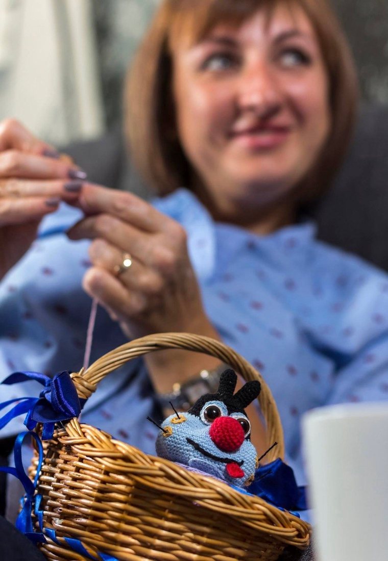 The maker of Tali Quokka crocheting, with a handmade toy in a wicker basket