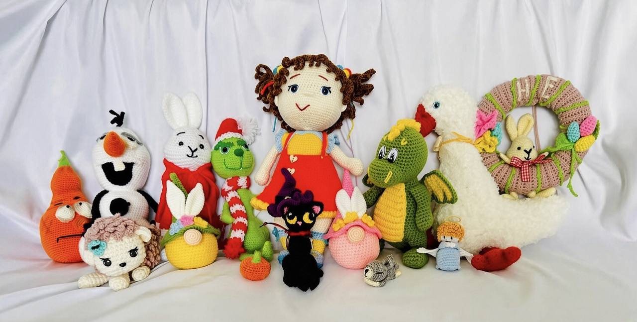 A family of handmade crochet toys sitting together on a white cloth